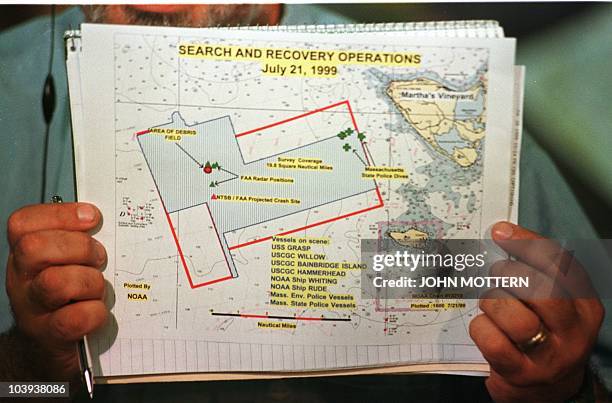 Television technician holds up the official handout map of the search and rescue area off Martha's Vineyard, MA, before a press conference 21 July,...