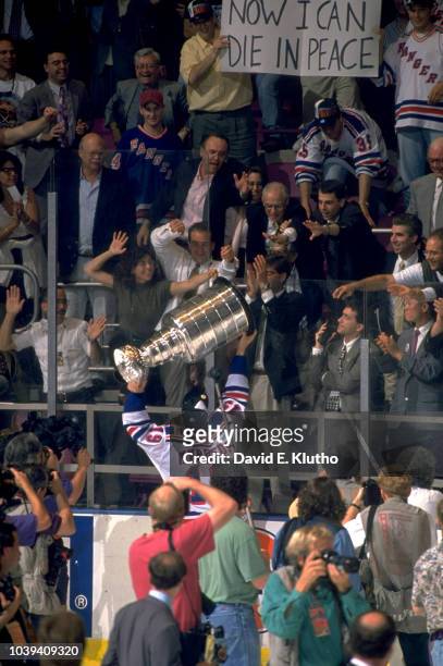 New York Rangers Nick Kypreos victorious holding up Stanley Cup to fans in stands after winning game and series vs Vancouver Canucks at Madison...