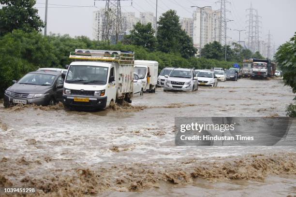 Vehicles wade through a waterlogged street after heavy rains at Golf Course Extension Road near Emaar building Sector 66, on September 24, 2018 in...