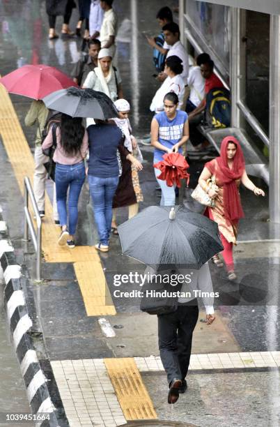 Commuters shelter under umbrellas as it rains at ITO on September 24, 2018 in New Delhi, India. The continuous downpour throughout the day leads to a...