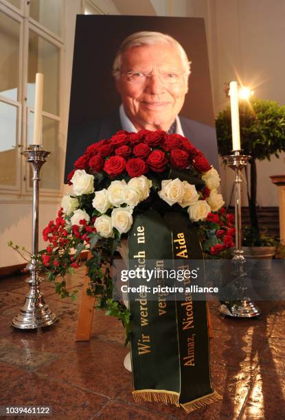Red and white roses and ribbon which reads 'we will never forget you - Almaz, Nicolas and Aida' are placed in front of a portrait of Karlheinz Boehm...