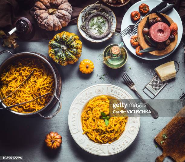 spaghetti with pumpkin bolognese in plate and cooking pot on kitchen table - spaghetti stock-fotos und bilder