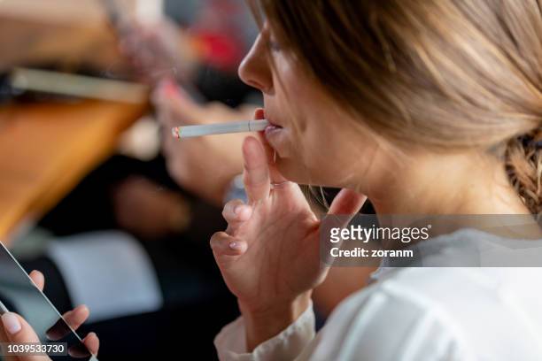 zakenvrouw kijken naar telefoon, roken sigaret - smoker stockfoto's en -beelden