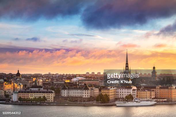 sunset or sunrise sky over riddarholmen chruch in gamla stan old town with boat for transportation in water and view of stockholm city, where is the popular landmark for travel stockholm, sweden, europe - stockholm imagens e fotografias de stock