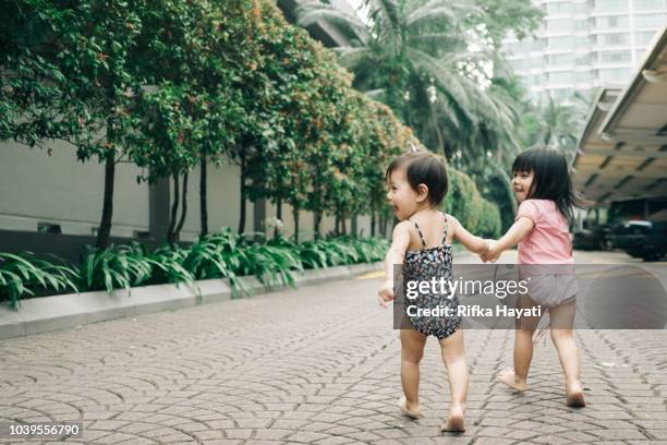 asian kids walking together holding hands - sister stock pictures, royalty-free photos & images