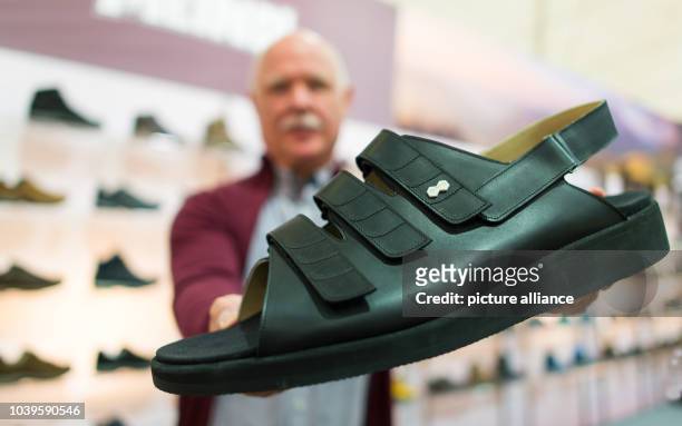 Shoe salesman Georg Wessels holds up a hand-made size 66 shoe at the GDS trade fair in Duesseldorf, Germany, 10 February 2016. For years Wessels'...