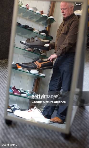 Shoemaker Georg Wessels places oversized men's shoes on a shelf in his shop in Vreden, Germany, 15 April 2013. Wessels manufactures shoes for people...