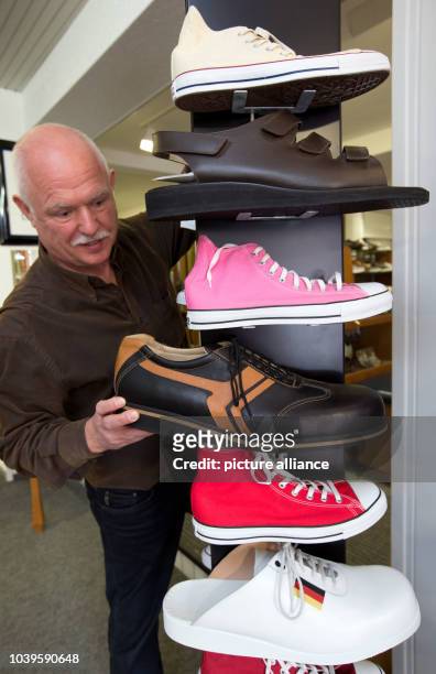 Shoemaker Georg Wessels places oversized men's shoes on a shelf in his shop in Vreden, Germany, 15 April 2013. Wessels manufactures shoes for people...