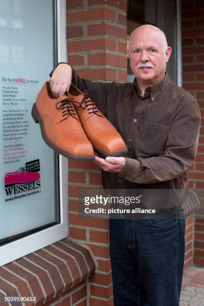 Shoemaker Georg Wessels presents a pair of oversized men's shoes in front of his shop in Vreden, Germany, 15 April 2013. Wessels manufactures shoes...