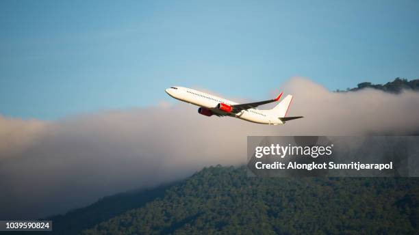 plane taking off over mountain range at morning with cloud. - red plane stock pictures, royalty-free photos & images
