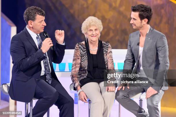 German television presenter Florian Silbereisen sits on stage with singer Semino Rossi and his mother Esther during the taping of the popular folk...