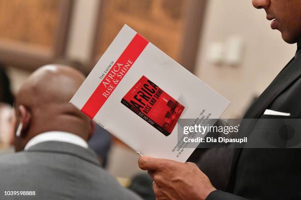 An attendee reads a program during a discussion of the book Africa Rise And Shine: How A Nigerian Entrepreneur From Humble Beginnings Grew A Business...