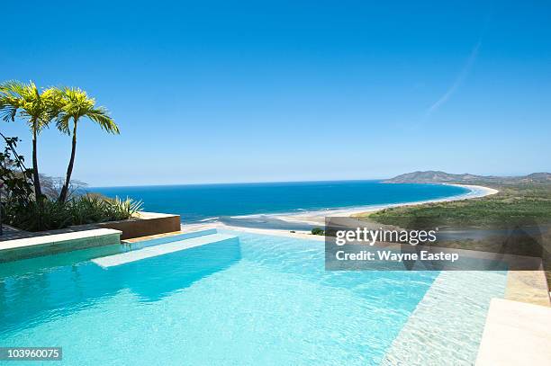 infinity pool overlooking beach and pacific ocean - swimming pool no people stock pictures, royalty-free photos & images