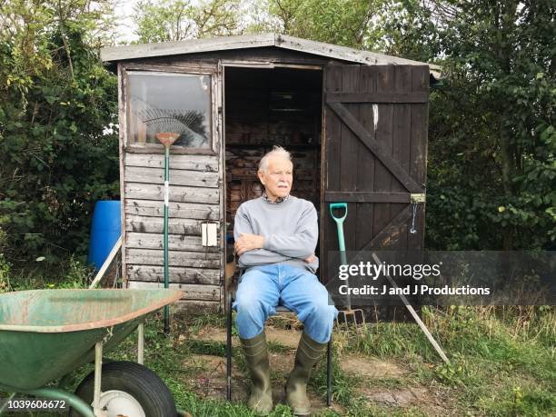 senior man sitting on a chair outside of his garden shed - gardening shed stock pictures, royalty-free photos & images