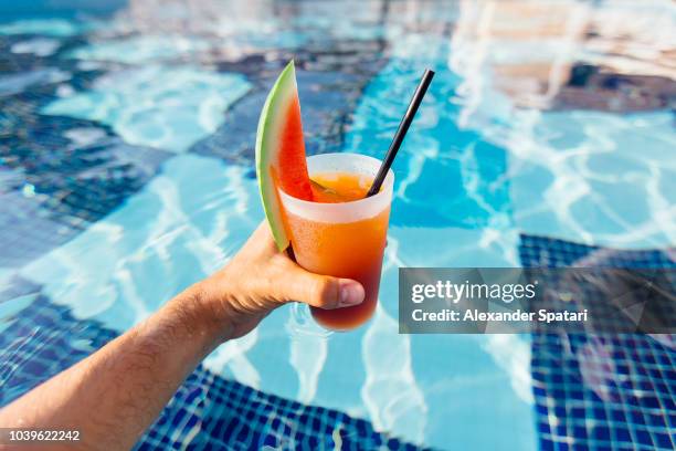 personal perspective view of drinking watermelon cocktail in swimming pool - swimming pool and hand stock-fotos und bilder