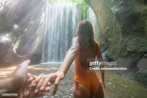 follow me to concept- young woman leading boyfriend to the tropical rainforest in bali. people travel nature concept. - bali waterfall stock pictures, royalty-free photos & images