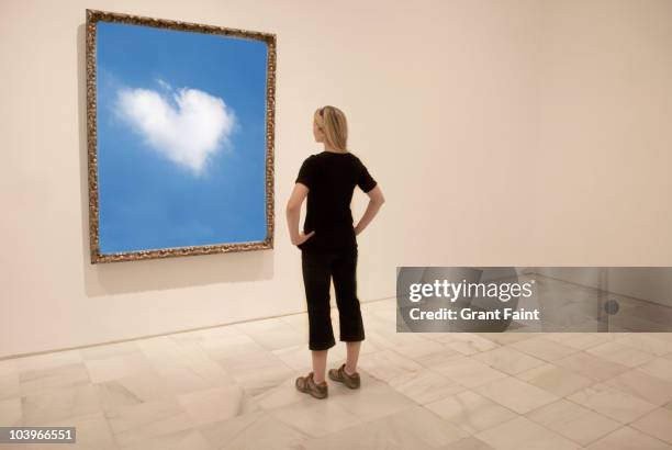 young woman looking at framed photograph - looking at a painting stock pictures, royalty-free photos & images