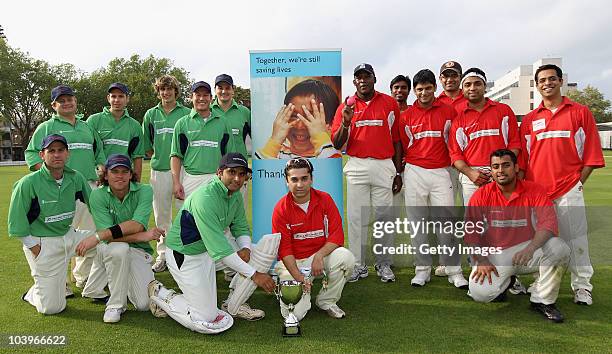 The teams from Herbert Smith and UBS pose with the trophy after tying the Save the Children Charity Match during the Save the Children Charity...