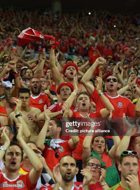 Supporters of Wales cheer to their team after losing the UEFA EURO 2016 semi final soccer match between Portugal and Wales at the Stade de Lyon in...