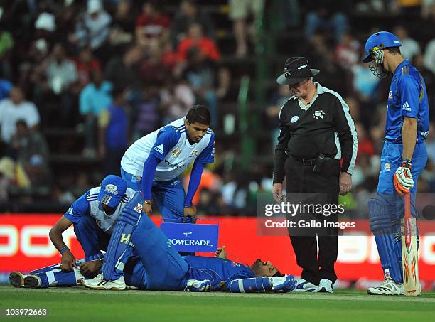 Umpire Rudi Koertzen watches over Harbhajan Singh, who receives medical attention while lying injured on the pitch during the Airtel Champions League...