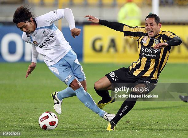 Leo Bertos of the Phoenix is hit heavily in a challenge from Hirofumi Moriyasu of Sydney during the round six A-League match between the Wellington...