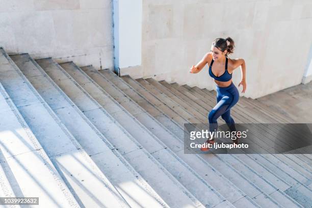 photo of sports woman running up outdoor stairway - forward athlete stock pictures, royalty-free photos & images