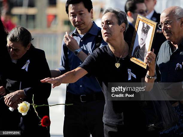 Woman holds a picture and drops flowers into a reflecting pool at Ground Zero during the annual memorial service for September 11, 2010 in New York...