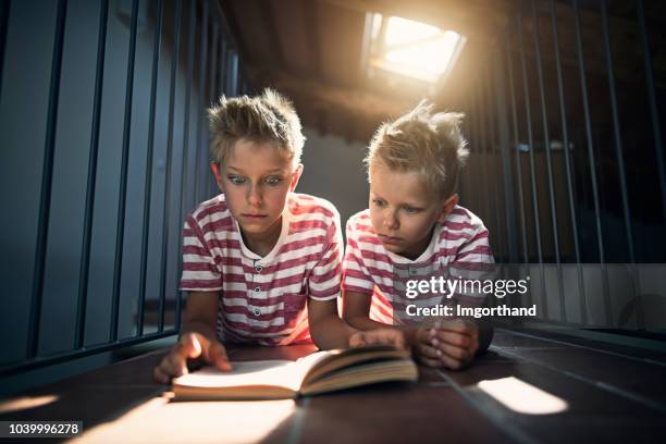 twins lezen van een eng boek op de zolder - cute twins stockfoto's en -beelden