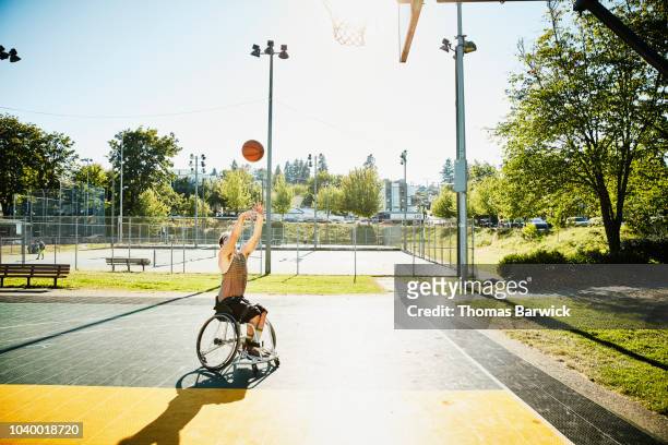 adaptive athlete playing basketball on outdoor court on summer afternoon - medicine ball stockfoto's en -beelden