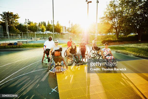 Portrait of group of adaptive athletes on outdoor basketball court after practice on summer evening