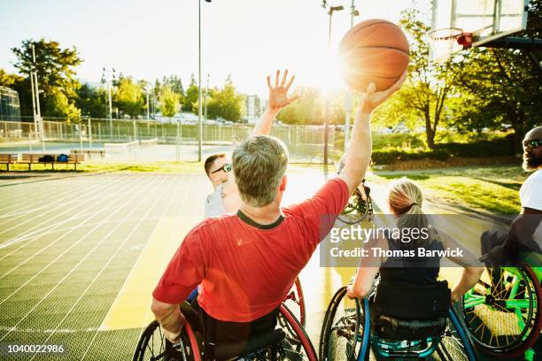 Adaptive athlete preparing to shoot ball during wheelchair basketball game on summer evening