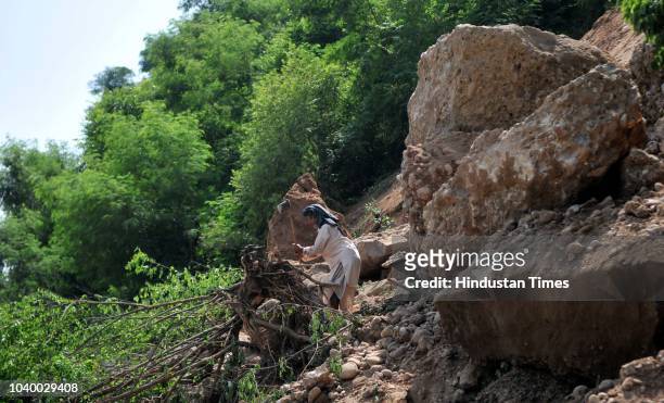 Man cuts tree near the remains of a damaged road after landslides hit the circular road on the outskirts of Jammu, on September 25, 2018 in Jammu,...