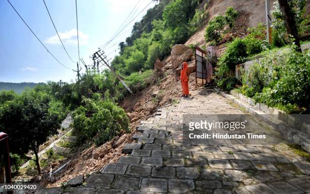 Priest stands near the remains of a damaged road after a landslides hit circular road on the outskirts of Jammu, on September 25, 2018 in Jammu,...