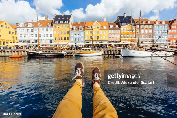 personal perspective point of view of man sitting at the nyhavn canal in copenhagen, denmark - beautiful legs and feet fotografías e imágenes de stock