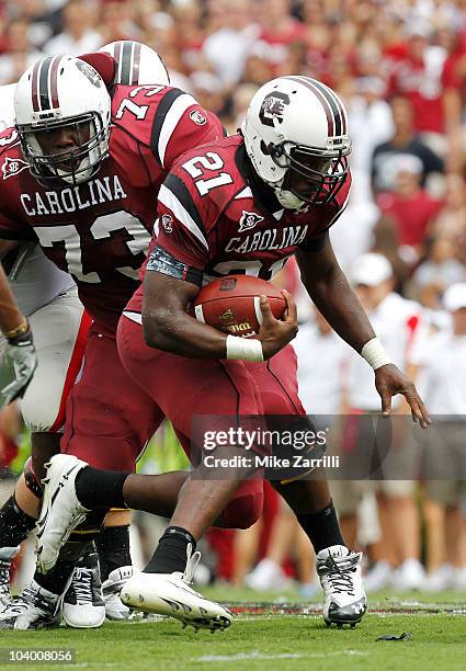 Tailback Marcus Lattimore of the South Carolina Gamecocks runs with the ball while guard Rokevious Watkins looks on during the game against the...