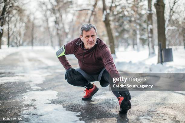 man warming up before jogging - active seniors winter stock pictures, royalty-free photos & images