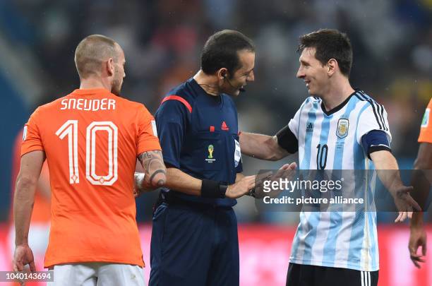 Turkish referee Cuneyt Cakir talks to Argentina's Lionel Mesi and Wesley Sneijder of the Netherlands during the FIFA World Cup 2014 semi-final soccer...