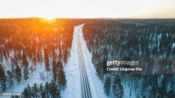 scenic aerial view of beautiful sunrise over forest and road in winter, lapland, finland - lappland aerial view stock-fotos und bilder