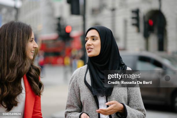 fröhlich freunde gehen zusammen in der stadt - arab woman walking stock-fotos und bilder