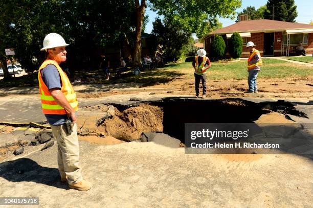 Denver water department officials look into a large sinkhole that Denver Fire Department ladder truck, Tower 23, was stuck in for hours on Zuni...