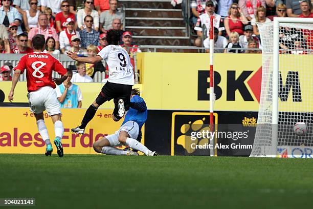 Srdjan Lakic of Kaiserslautern scores his team's first goal against Radoslav Zabavnik and goalkeeper Christian Wetklo of Mainz during the Bundesliga...