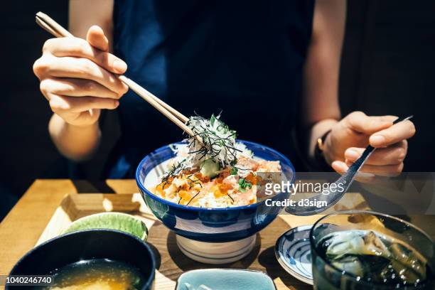 close up of woman enjoying freshly served traditional japanese seafood donburi with chopsticks in a restaurant - chopsticks stock pictures, royalty-free photos & images