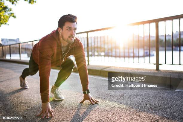 young sporty man runner in a starting position outside in a london city at sunset. - england slovakia stock pictures, royalty-free photos & images