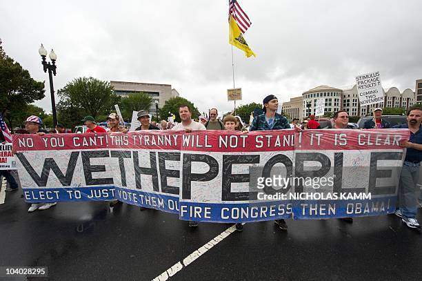 Demonstrators carry a banner calling for the voting out of the US Congress and of President Barack Obama during a march by supporters of the...