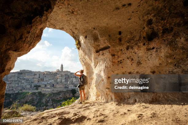 donna che guarda la vista da una grotta di matera, basilicata, italia - scoperta foto e immagini stock