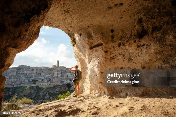 vrouw kijken naar weergave van een grot van matera in basilicata, italië - basilicata stockfoto's en -beelden