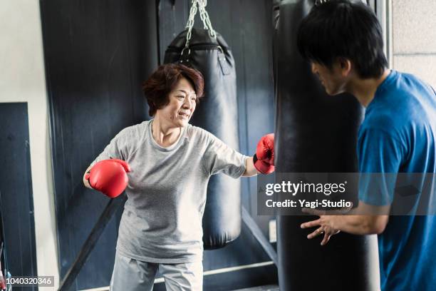 mujer adulta mayor entrenamiento en el gimnasio de boxeo con el entrenador - kick boxing fotografías e imágenes de stock