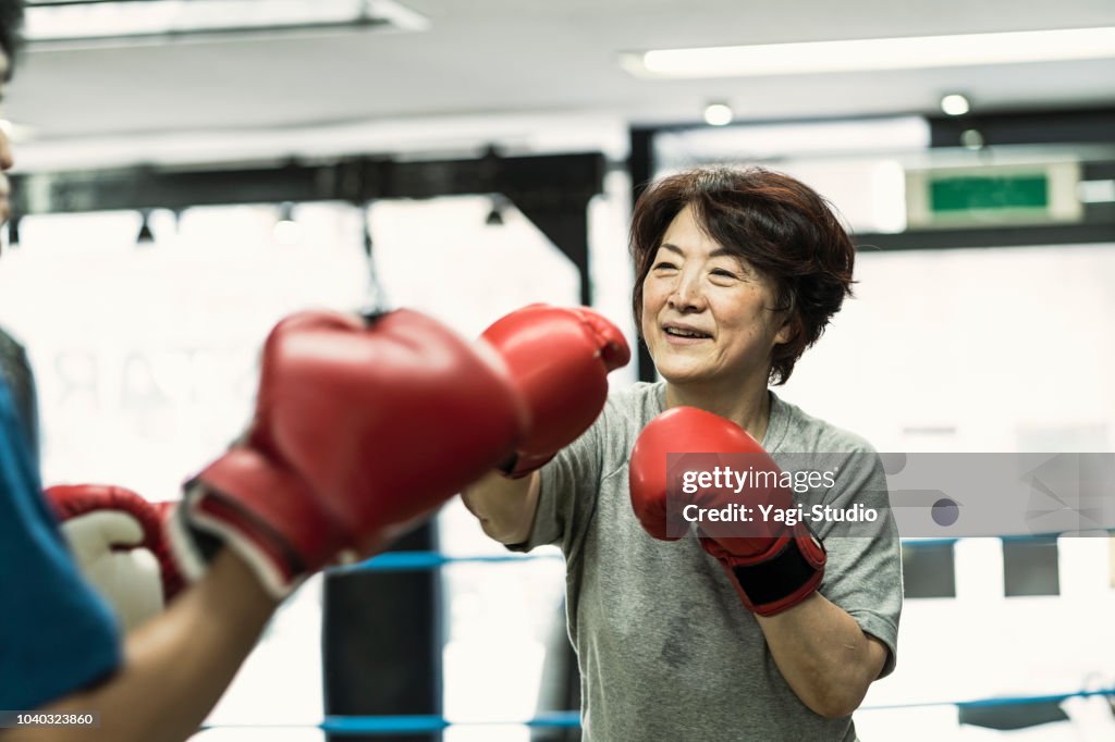 Senior adult women training with male instructor at boxing gym