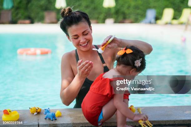 mother and baby girl at swimming pool - baby suncream stock pictures, royalty-free photos & images