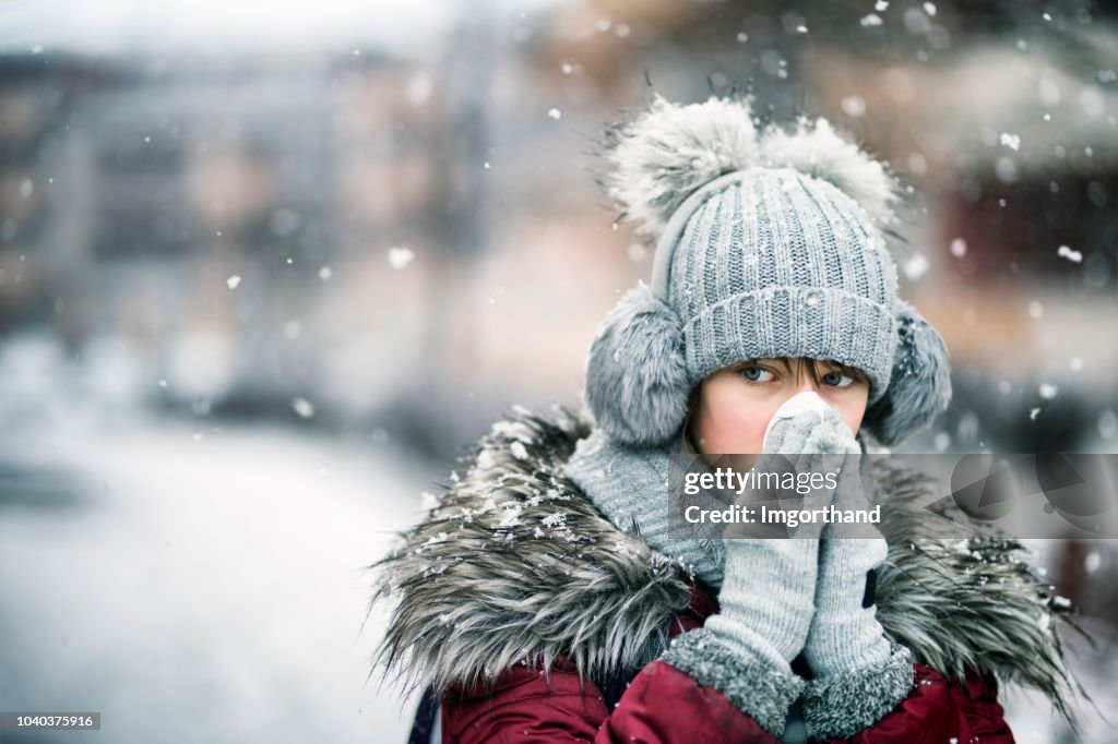 Teenage girl blowing nose on winter day